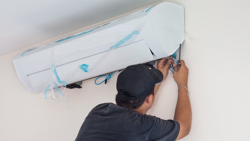Man worker installs indoor air conditioner in the new home. Select focus