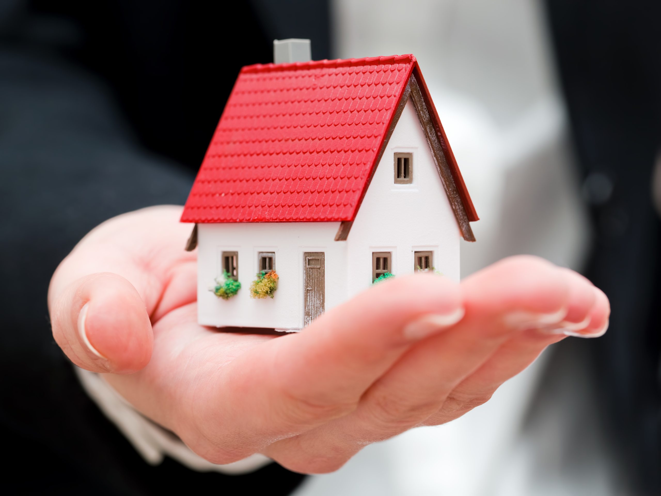 A real estate agent holding a small new house in her hands